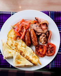 um prato de alimentos com ovos, salsichas e legumes em GLAMOUR APOLLO HOTEL em Webuye