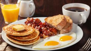 um prato de pequeno-almoço com ovos, bacon e torradas em GLAMOUR APOLLO HOTEL em Webuye