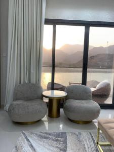 two chairs and a table in a room with a large window at Great Escape for family and friends 4BR Villa with Private Pool and Sea View in Fujairah