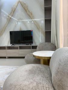 een woonkamer met 2 stoelen, een tafel en een tv bij Great Escape for family and friends 4BR Villa with Private Pool and Sea View in Fujairah