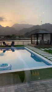 a large swimming pool with a gazebo and mountains at Great Escape for family and friends 4BR Villa with Private Pool and Sea View in Fujairah