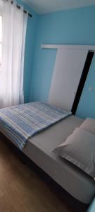 uma cama num quarto com uma parede azul em Hôtel de France em Limoges