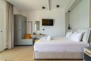 a white bedroom with a white bed and a bathroom at Luxury SeaSide Suites in Hersonissos