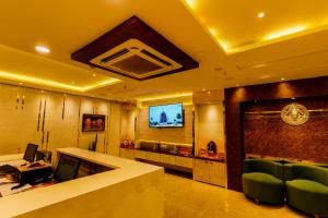 a lobby with a desk and a television and green chairs at Xenious Hermitage Koshal, Puri in Puri