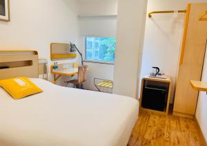 Schlafzimmer mit einem weißen Bett, einem Schreibtisch und einem Tisch in der Unterkunft bloomrooms @ City Centre in Bangalore