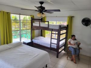 a woman sitting in a chair in a bedroom with bunk beds at Ocean View in Big Corn Island