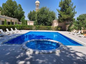 a swimming pool with chairs and a building at Orient Star Hotel in Samarkand