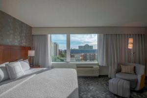 a bedroom with a bed and a chair and a large window at Courtyard by Marriott Bethesda Chevy Chase in Bethesda