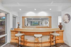 a bar with stools in a room with a mirror at Grand Slam Getaway with Tennis Court and Heated Pool in Kewarra Beach