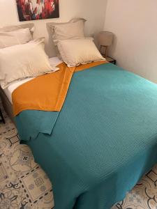 a large bed with a green and orange blanket at Petit nid Catalan , 10 minutes des plages in Perpignan
