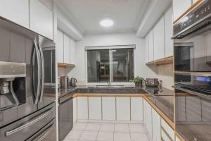 a kitchen with white cabinets and a stainless steel appliances at Grand Slam Getaway with Tennis Court and Heated Pool in Kewarra Beach