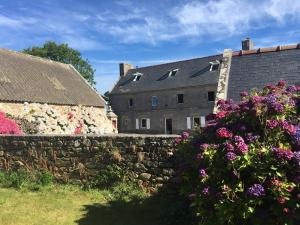 a house with flowers in front of a stone wall at La maison de Gwen in Cléden-Cap-Sizun