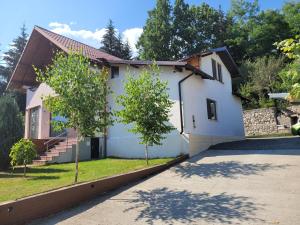 a white house with two trees in the driveway at MaDaS in Bărbăteşti