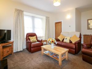 a living room with a couch and chairs and a tv at Katmoget Cottage in Cupar