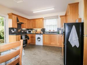 a kitchen with wooden cabinets and a black refrigerator at Katmoget Cottage in Cupar