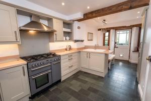 uma cozinha com armários brancos e um forno com placa de fogão em Barf Cottage em Portinscale