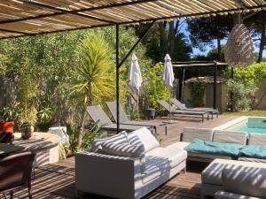 un patio con muebles blancos y una piscina en La Vagabonde, en Saint-Tropez