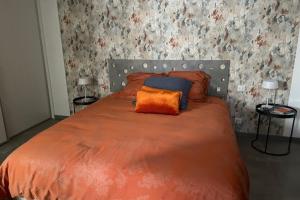 a bedroom with a bed with orange sheets and two lamps at Studio pour 2 personnes proche Canal du Midi - Ventenac en Minervois in Ventenac en Minervois