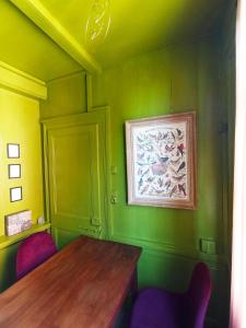 a green room with a wooden table and purple chairs at A Vol D'Oiseau in Honfleur