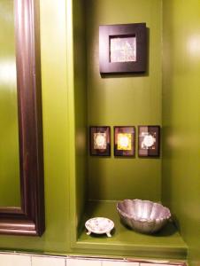 a green wall with a bowl on a shelf with pictures at A Vol D'Oiseau in Honfleur