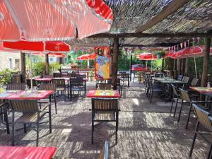 een openluchtrestaurant met tafels, stoelen en parasols bij Hôtel Etape in Les Omergues