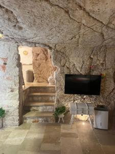 a stone wall with a television in a room with stairs at Grotta Carlotta in Ostuni
