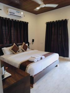 a bedroom with a large bed with brown curtains at Winterfeel Resort in Alleppey