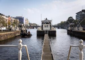 a boat is docked on a river with a dock at Pride Amsterdam Canal 'SWEET' Weekend in Amsterdam