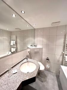 W łazience znajduje się umywalka, toaleta i lustro. w obiekcie Hotel Sonnenberg Garni w mieście Hinterzarten