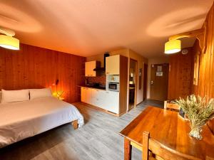Fontaine du Mont Blanc Hotel & Spa في لي أوش: غرفة نوم بسرير وطاولة ومطبخ