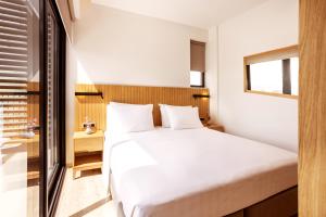 um quarto com uma cama branca e uma janela em DAYS City Suites Athens em Atenas