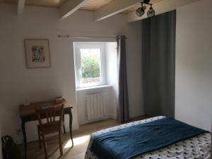 a bedroom with a bed and a desk and a window at La maison de Gwen in Cléden-Cap-Sizun