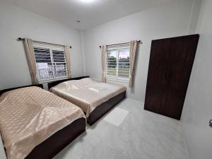 a bedroom with two beds and a cabinet and two windows at PPN Garden Resort in Suwannaphum