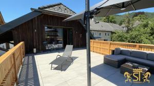 a patio with a blue couch and an umbrella at Chalet Münsterstadl in Altmünster