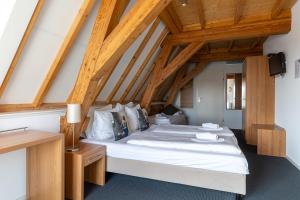 a large bed in a room with wooden ceilings at Hotel Stad aan Zee Vlissingen in Vlissingen