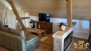 ein Wohnzimmer mit einem Sofa und einem TV in der Unterkunft Chalet Münsterstadl in Altmünster