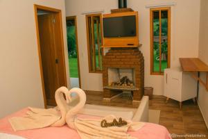 two towel swans sitting in a room with a fireplace at Pousada das Flores in Gonçalves