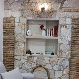 a stone wall with a shelf with books and a vase of roses at Boutique Eptalofos 15min from airoport and sea in Kouvarás