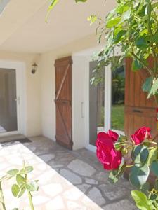 a porch with red roses and a door at L'Imprévu in Bourisp