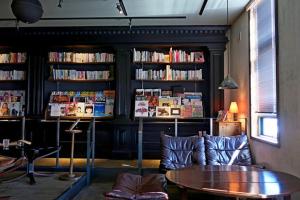 a living room with a table and book shelves with books at Fuji Cottage in Fujikawaguchiko
