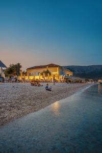 a person sitting on a beach near the water at Hotel Dobrovit in Baška