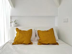 a white bed with two yellow pillows on it at Art Cottage with oPorto View! in Vila Nova de Gaia