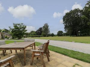 een houten picknicktafel en stoelen naast een weg bij Conors Cottage in Denbigh