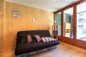 a couch sitting in a room with wooden walls at Les Anglines - Appt proche station de ski in Les Angles