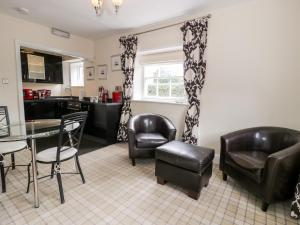 a living room with a table and chairs and a kitchen at Lower Gardener's Cottage in Denbigh