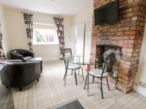 a living room with a glass table and a brick fireplace at Lower Gardener's Cottage in Denbigh