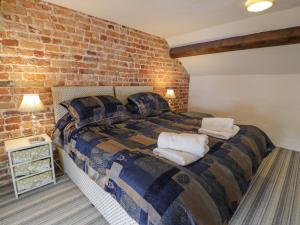 a bedroom with a large bed with a brick wall at Walled Garden Cottage in Denbigh