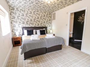 ein Schlafzimmer mit einem Bett mit einer schwarzen und weißen Decke in der Unterkunft Lower Gardener's Cottage in Denbigh
