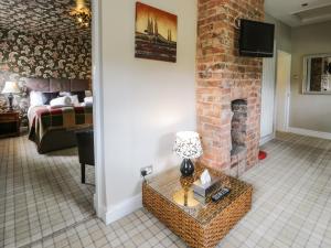 a living room with a brick fireplace and a couch at Upper Gardener's Cottage in Denbigh