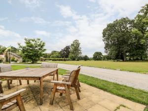 patio con tavolo da picnic in legno e sedie. di Lower Gardener's Cottage a Denbigh